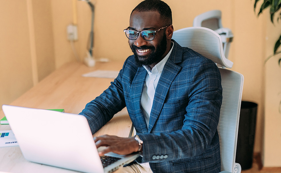 A man smiling while working on a laptop.