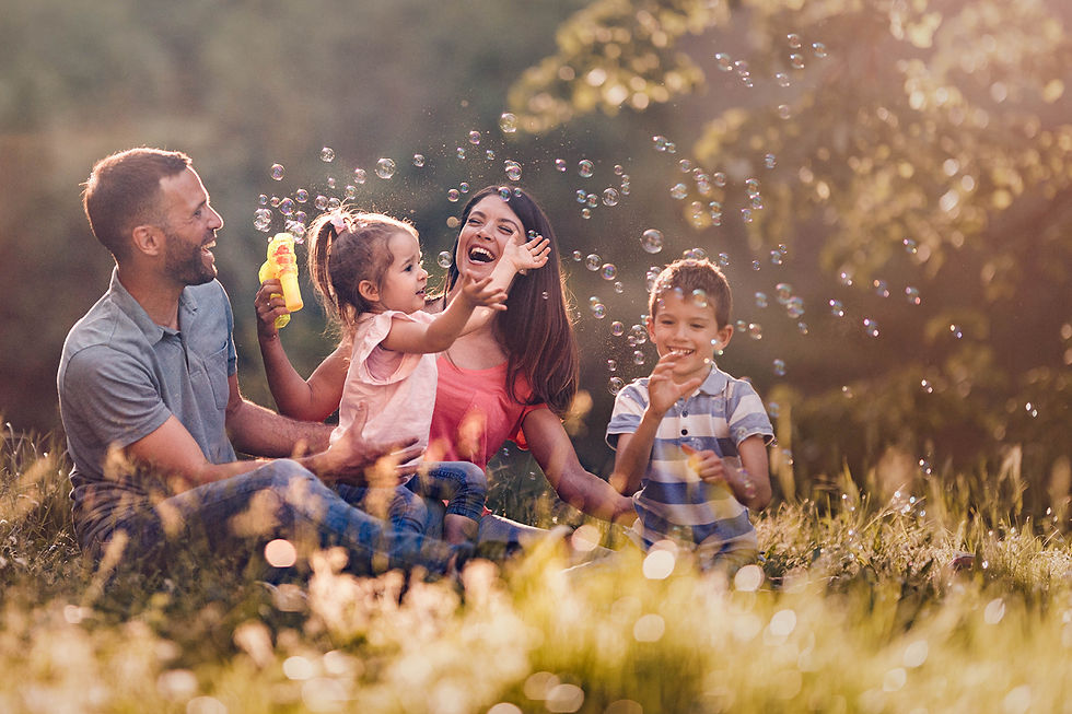Happy family playing with bubbles in a sunny park.