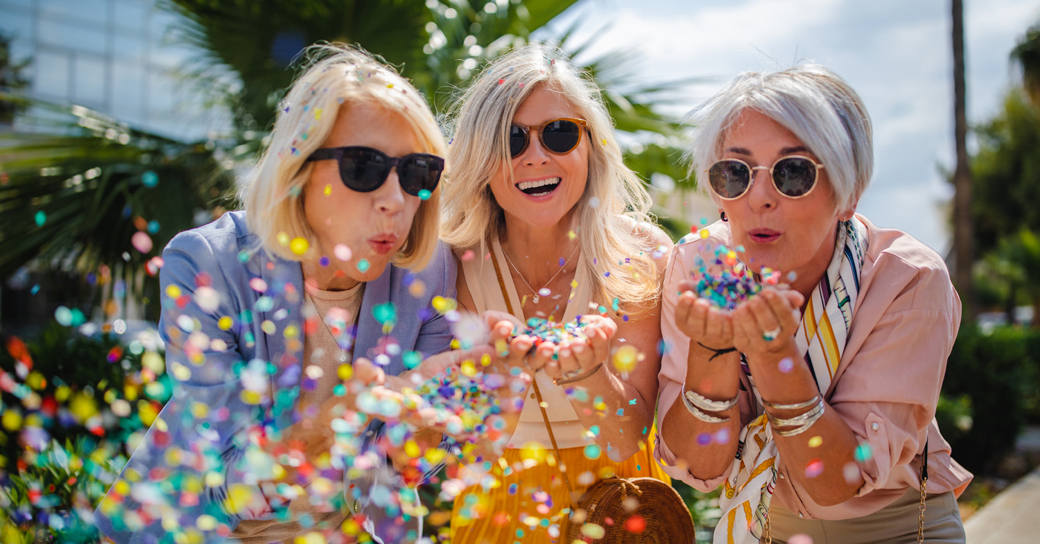 Happy women blowing confetti